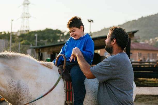 boy with special needs developing motor skills on horses